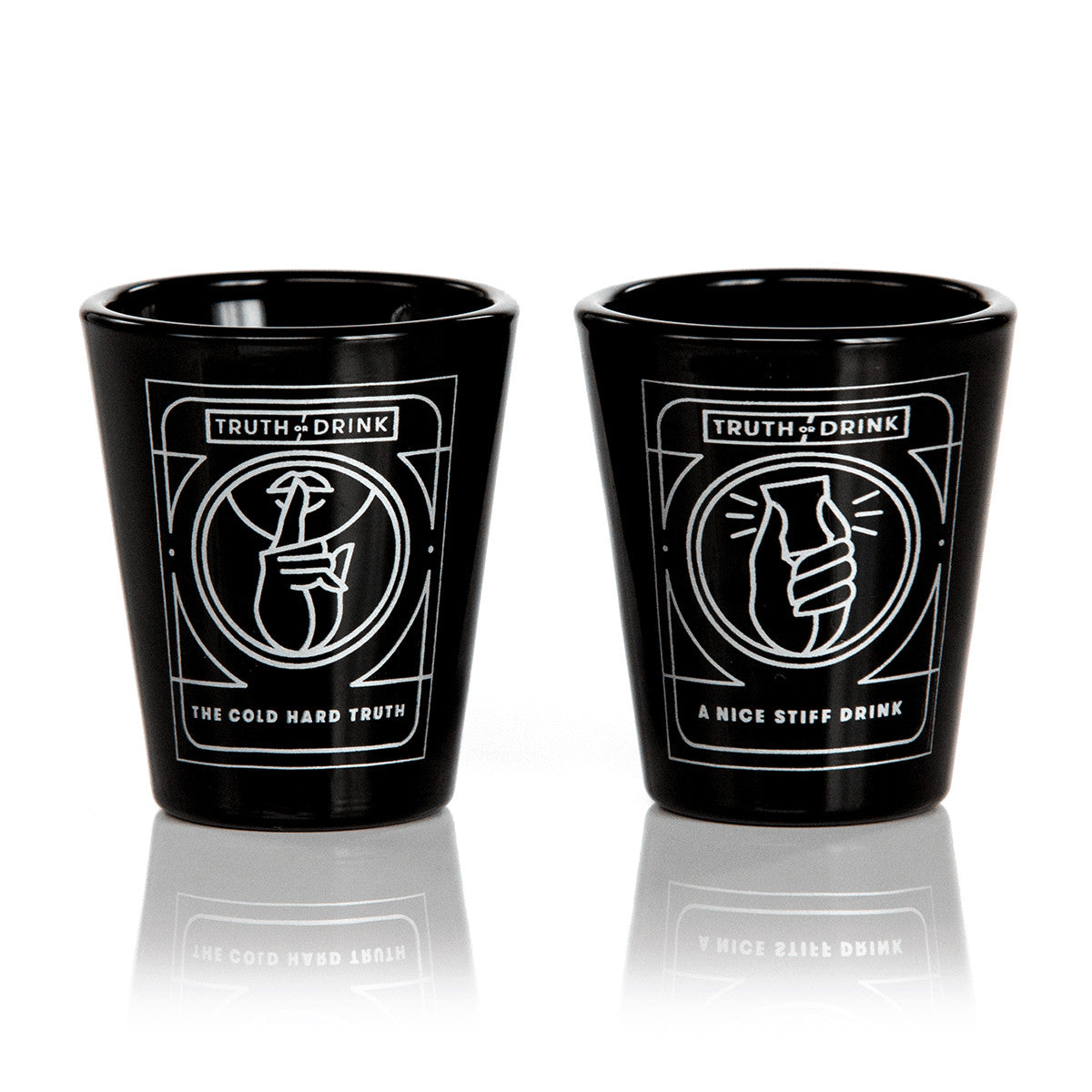 Two black shot glasses with white geometric designs one depicting a hand shushing the other a hand clutching a drink